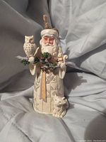 Front view of Jim Shore Woodland Santa figurine holding branch with white owl and small bird, with a small dog at base.