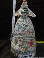 Front view of the Jim Shore figurine showing winter landscape scenes on the dress and the angel holding a decorated tree.