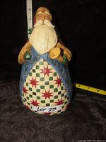 Front view of the Santa figurine showing detailed quilt pattern robe and bell.