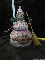Front and side view of the snowman figurine showing detailed painting and the broom held by the snowman.