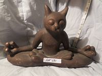 Photo showing single ceramic bronze-tone meditating cat statue with closed eyes, sitting cross-legged in a yoga pose with hands forming mudra gesture.