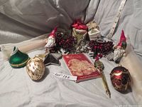 Wide view of all items in the lot arranged on fabric background: two pewter gnomes, two snowflake candleholders with red berry accents, beeswax candles in decorative boxes, two small ornaments (green round and teardrop-shaped), and Santa's Magic Wish List booklet.