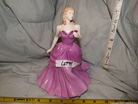Front view of the Royal Doulton Pretty Ladies 2005 Victoria figurine with measuring tape showing size and a sign labeled LOT 99.