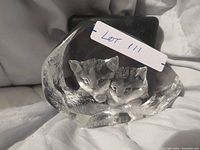 Front view of first crystal paperweight showing detailed cat heads inside oval base