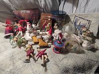 Wide view of various skating and winter-themed figurines and ornaments laid out showing the full assortment including skaters, snowmen, and the warming house.