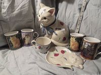 Photo showing the full set of items including the Lenox cat cookie jar, matching spoon dish, cup, and four Lesley cat mugs.