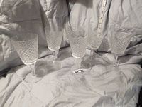 Five Waterford crystal wine goblets in Alana pattern arranged on fabric background with measuring tape showing height around 6-7/8 inches