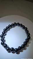 Photo of chunky 8mm hematite bead stretchy bracelet arranged in circle showing uniform size and shine of beads.