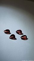 Four pear-shaped natural garnet gemstones on a plain surface, showing clarity and color