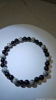 Top down image of a round stretchy bracelet made of black onyx and map jasper 6mm beads.
