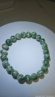 Top view of the round chunky 8mm green spotted jasper bead bracelet laid flat in a circular shape.