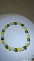 Image of natural multicolored jade bracelet laid flat showing yellow, green, and white jade beads.