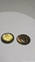 Two oval natural labradorite cabochon gemstones showing distinct golden and orange flashes on plain white background.
