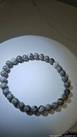 Top view of natural map jasper beaded bracelet showing round gray beads with dark vein patterns on elastic cord