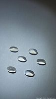 Photo showing six oval natural white moonstone cabochons with translucent milky white color and smooth polished surface.