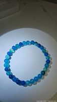 Front view of the ocean blue agate bracelet formed into a circle showing the bead coloration and polished finish.