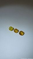 Three round yellow sapphires placed on a white background, exhibiting deep yellow color and faceted cuts.