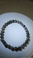 Yooperlite stretchy bracelet displayed on a white background, showing round grayish gemstone beads with natural patterns.