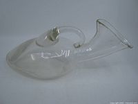 Side view of clear glass urinal showing overall shape and handle