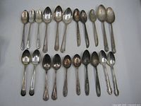 All 21 silverplate teaspoons laid out in two rows, bowl side up.
