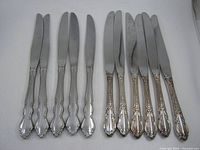 Front view of eleven silverplate knives, two patterns