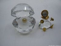 Baby girl figurine beside open crystal clam shell with pearl