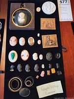 Top-down photo showing entire collection of antique and vintage cameos arranged on black display.