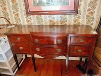 Front angled view of the antique Drexel buffet showing wood grain, curved drawer fronts, metal handles and wooden legs.