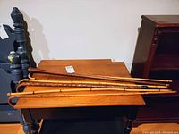 Four bamboo and wood canes resting on wooden furniture, curved handles visible, showing natural bamboo pattern and wood grain.