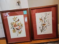 Full view of both framed prints standing side-by-side showing overall condition and framing style.