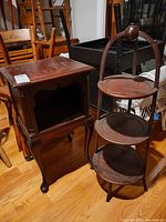 Side view of wooden end table with open storage and wooden tiered pie stand with three circular shelves and curved supports