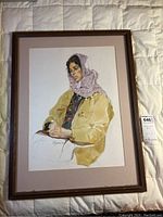 Full view of framed watercolor portrait showing woman with yellow jacket and purple headscarf.