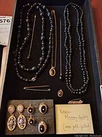 Full view of entire Victorian mourning jewelry set on black tray, including necklaces, earrings, pins, and pendant. Captures variety and condition of pieces.