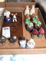 Full view of all salt and pepper shakers in the lot arranged inside a cardboard box on a brown paper surface.