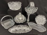 Photo showing all cut glass items in lot including bowls, vase, basket-shaped bowls, and plates