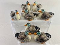 Eight ceramic duck-shaped soup bowls arranged on display, all with removable wings positioned beside or on top.