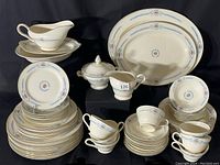 Photo of entire matching Edwin M. Knowles china dinnerware set with blue floral pattern spread out and stacked, showing all included items such as plates, cups, saucers, platters, serving pieces.