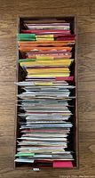 Top view of wicker basket filled with neatly organized greeting cards arranged by color and separated by dividers.