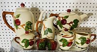 Group view of tall coffee pot, creamer, teapot, sugar bowl and apple-shaped shakers