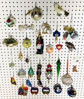 Photo showing a collection of assorted glass ornaments hanging on a pegboard with various designs including fruits, animals, and train cars.