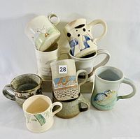 Photo showing all eight hand-thrown animal-inspired mugs arranged together, displaying various animal designs and shapes.