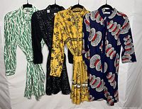 Four dresses hanging side by side, showing full front views of each dress in different colors and patterns.