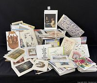 Wide view of over 200 assorted blank notecards arranged in scattered stacks and piles with visible variety in design and size.