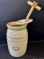 Butter churn full view showing ceramic vessel with wooden paddle inside.