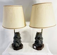 Pair of hippo table lamps on octagonal wooden bases with beige fabric shades. Both lamps show lamp shades with wear and aging.