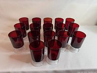Seventeen ruby red wine glasses arranged standing on a flat surface showing the set's appearance and quantity.