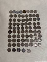 Top-down photo showing around 60 Canadian nickels arranged on a white textured surface.