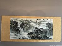 Photo showing the entire Chinese landscape painting with waterfall and mist, mounted on golden matting.