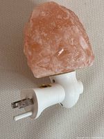 Front and side views of the Himalayan natural rock night light showing the salt rock and white plug-in base with on/off switch.