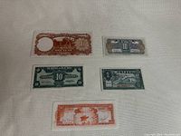 Five Chinese paper money notes laid out on a white fabric background showing various denominations and colors.